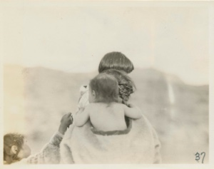Image of Eskimo [Inuk] baby on mother's back (rear view)